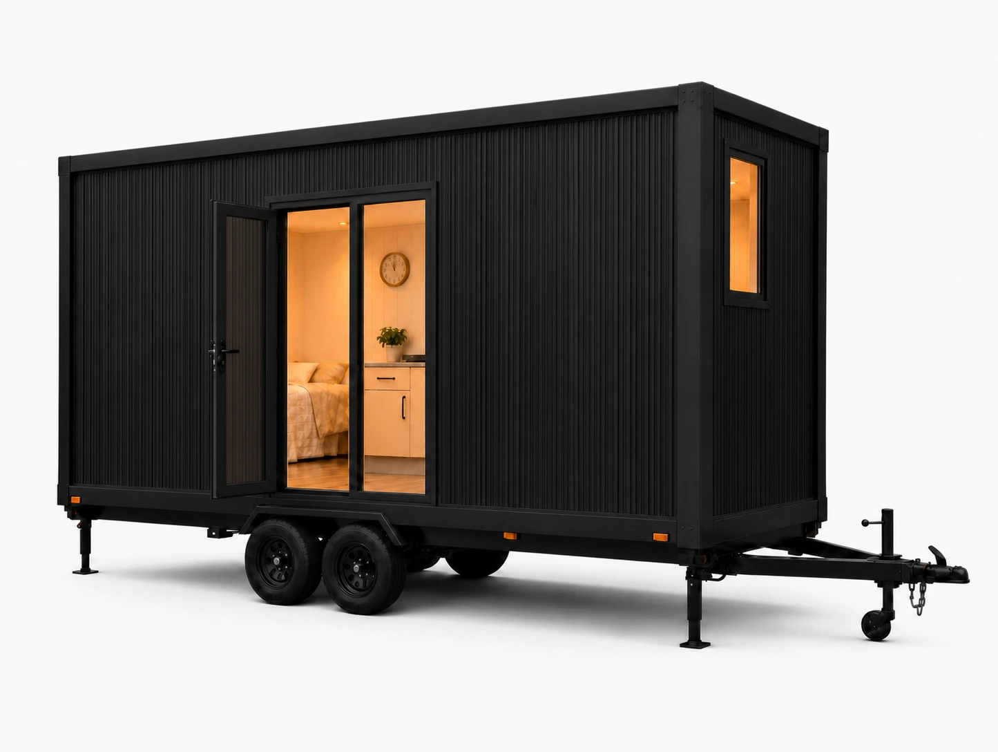 TINYpod exterior: all-black corrugated steel tiny home on a twin-axle registered trailer, sliding glass door open onto a warmly lit interior with a queen bed and pale timber kitchen.